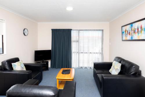 a living room with two black leather couches and a table at Fitzgerald on King in Timaru