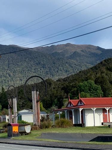 a house on the side of a road with mountains in the background at Blackball Tinyhouses in Blackball