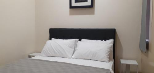 a bed with white pillows and a black headboard at Omar's Place 2 in Kuala Lumpur