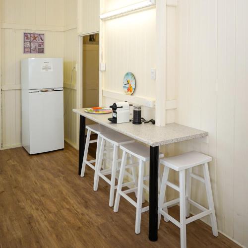 a kitchen with a white refrigerator and a counter with stools at Daggoombah Holiday Home Magnetic Island in Arcadia