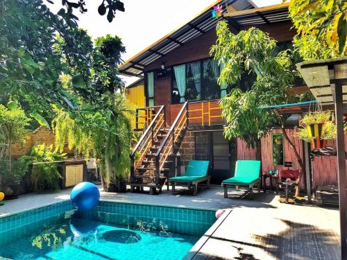 une maison avec une piscine en face d'une maison dans l'établissement De Wiang Kum Kam, à Chiang Mai
