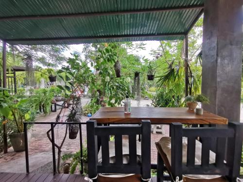 een houten tafel en stoelen op een patio met bomen bij Long Lake Resort in Ban Nong Pru