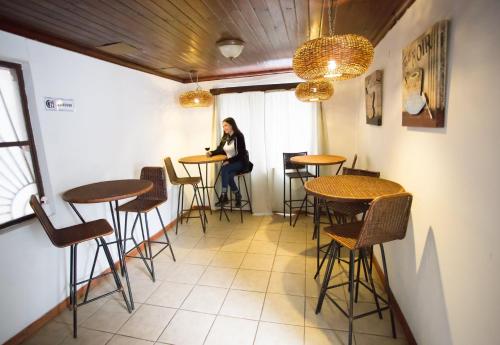 a woman sitting at a table in a room with stools at Hostal del Mimbre Chile in Santa Cruz