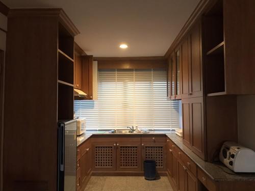 a kitchen with wooden cabinets and a sink and a window at Sunshine Gypsy at Beach Villa Vibhavadi Pattaya in Na Jomtien