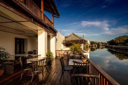 a balcony with tables and chairs next to a river at Punyashthiti villa in Chanthaburi