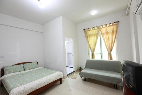 a bedroom with a bed and a couch and a television at Travelers Fu-Home in Hualien City