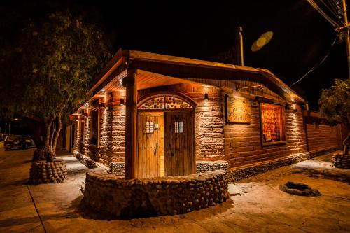 a small building with a wooden door at night at Hostal Sumaj in San Pedro de Atacama