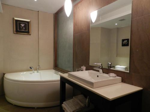 a bathroom with a tub and a sink and a bath tub at Sinclairs Retreat Ooty in Ooty