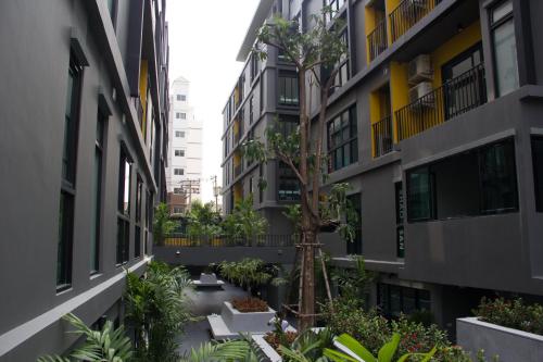 a courtyard between two buildings with a tree in the middle at iSanook Bangkok in Bangkok