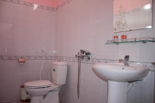 ein weißes Bad mit einem WC und einem Waschbecken in der Unterkunft Minh Anh Garden Hotel in Mui Ne