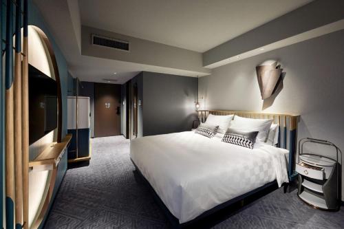 a bedroom with a large white bed and a television at Mercure Kyoto Station in Kyoto