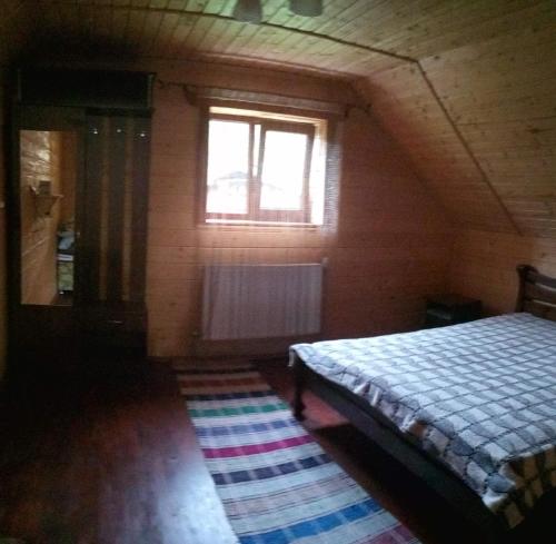 een slaapkamer met een bed, een raam en een tapijt bij Котедж біля річки in Kelechin