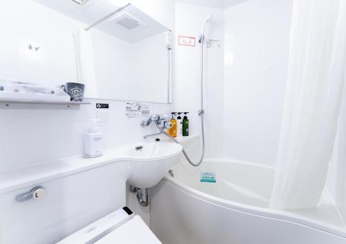 a white bathroom with a sink and a shower at APA Hotel Nagoya Sakae in Nagoya