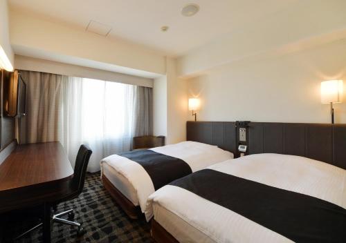 a hotel room with two beds and a desk at APA Hotel Nagoya Sakae in Nagoya