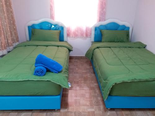 two twin beds in a room with green and blue at Baan Hin Sai Suay in Nong Sarai