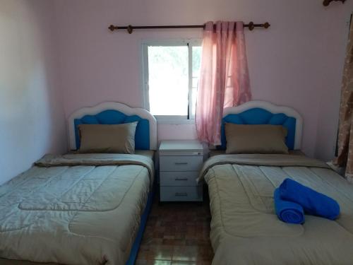 two beds in a small room with a window at Baan Hin Sai Suay in Nong Sarai