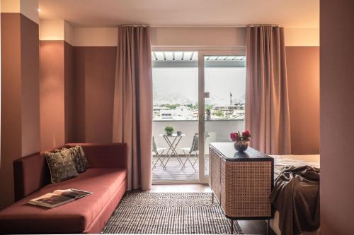 Habitación de hotel con sofá, cama y balcón en Hotel Luise, en Riva del Garda