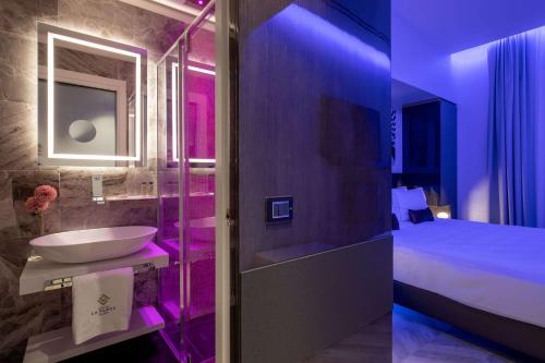 baño con lavabo y cama con luces moradas en Hotel La Place Roma, en Roma