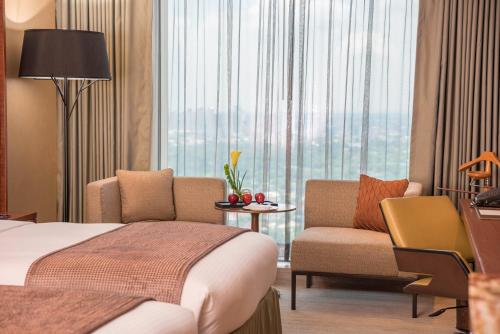 a hotel room with a bed and a chair and a window at Marco Polo Ortigas Manila in Manila