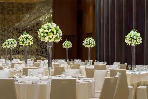 a dining room with white tables and chairs with flowers at Marco Polo Ortigas Manila in Manila