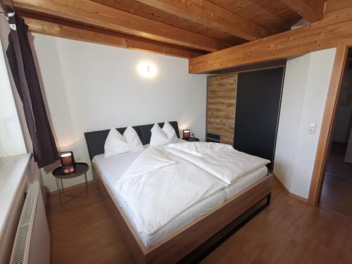 Cette chambre dispose d'un grand lit blanc et de plafonds en bois. dans l'établissement Ferienwohnung Ela, à Reutte