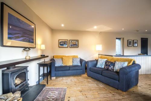 a living room with two blue couches and a fireplace at Rock Cottage - 3 Bedroom Holiday Home - Fishguard in Fishguard