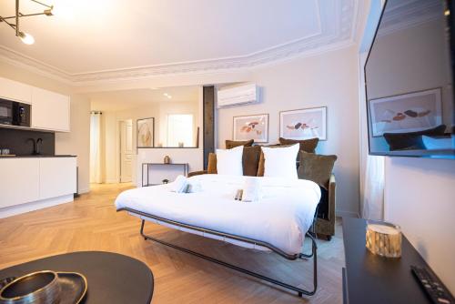 1 dormitorio con 1 cama blanca grande y escritorio en Luxury apartments in Paris Center, en París
