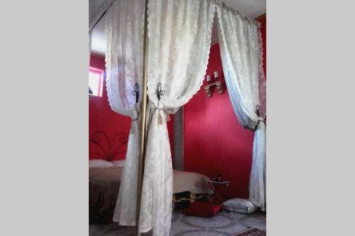 Schlafzimmer mit roten Wänden und einem Bett mit weißen Vorhängen in der Unterkunft Romantic Studio Apartment in the heart of the city in Komárom
