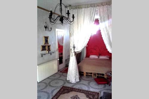 Un dormitorio con una cama con paredes rosas y una lámpara de araña. en Romantic Studio Apartment in the heart of the city en Komárom
