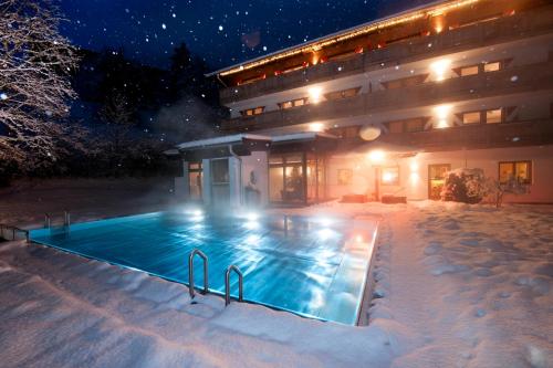 a swimming pool in the snow in front of a building at Ferienappartements Landhof in Ellmau
