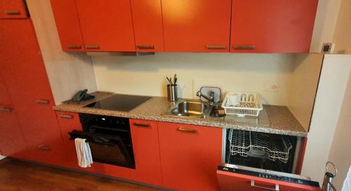a red kitchen with a sink and a stove at Sensi Living Station in Pfäffikon