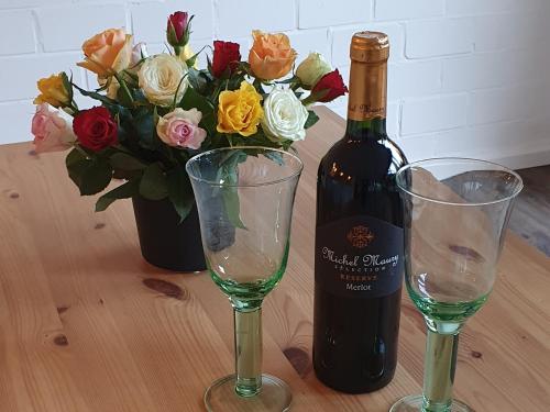 eine Flasche Wein und zwei Gläser auf dem Tisch mit Blumen in der Unterkunft Charmant und stilvoll in Kaarst