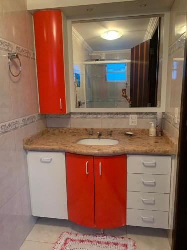 baño con lavabo y armario rojo en Apartamento em itapema, en Itapema