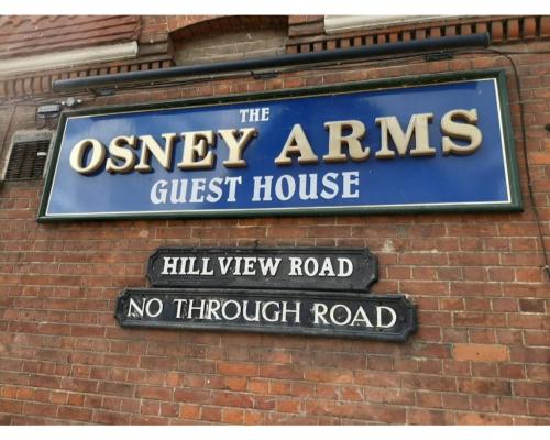 una señal para la casa de huéspedes de Oxney Arms en una pared de ladrillo en The Osney Arms Guest House, en Oxford
