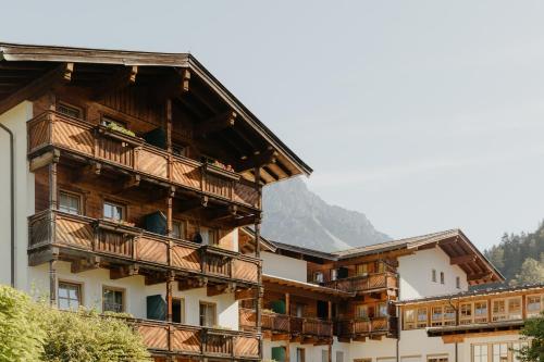 a building with wooden balconies and a mountain in the background at Hotel Kaiser in Tirol in Scheffau am Wilden Kaiser