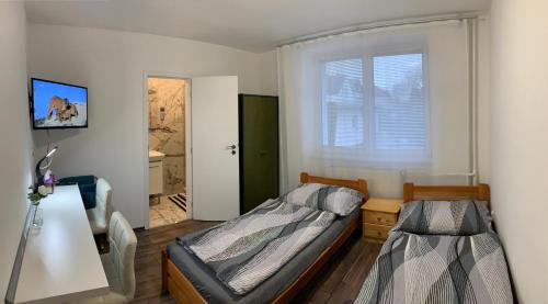 1 dormitorio con cama, escritorio y ventana en Pension Milada, en Klecany