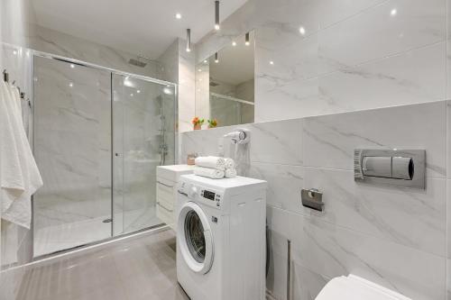 a white bathroom with a washing machine and a shower at Baltica Sky by TriApart in Gdańsk