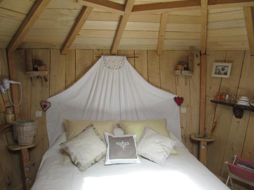 1 dormitorio con 1 cama blanca en una habitación con paredes de madera en Camping belle rivière, en Chaniers
