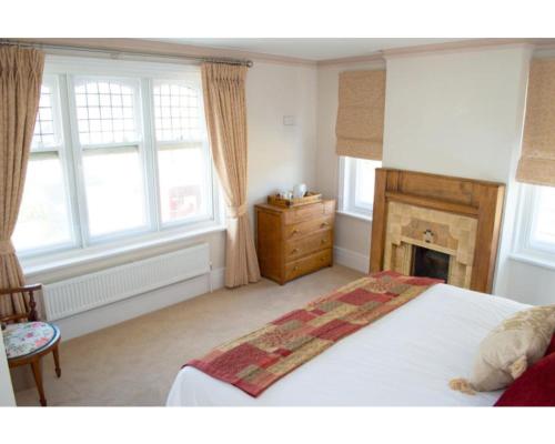 a bedroom with a bed with a fireplace and windows at The Osney Arms Guest House in Oxford