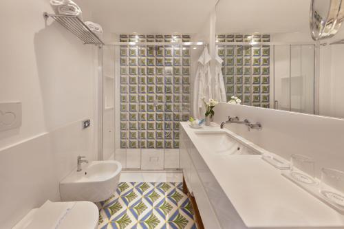 a white bathroom with a sink and a toilet at Grand Hotel Riviera in Sorrento