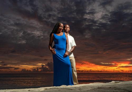 a man and a woman standing on the beach with a sunset at Olhumathi View Inn in Ukulhas