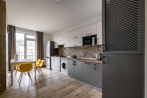 a kitchen with white cabinets and a table and chairs at City Aparts Kulisha Str in Lviv