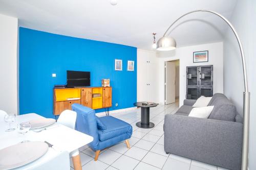 uma sala de estar com um sofá e uma parede azul em L Art est Union - joli T1 à 5min à pied de la plage de Boucan Canot em Saint-Gilles-les-Bains
