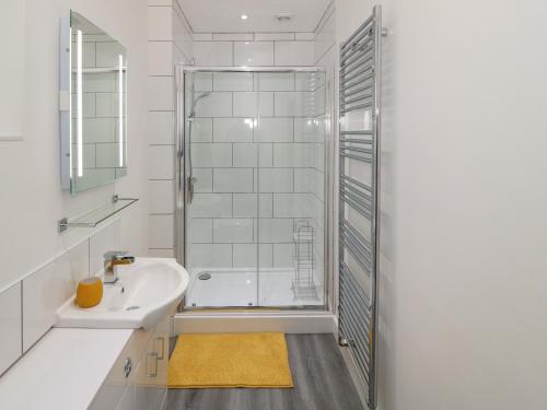 une salle de bain blanche avec une douche et un lavabo dans l'établissement Berth, à Pwllheli