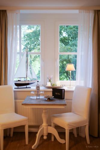 a table and two chairs with a sailboat in a window at Hotel Hof Holm in Brasilien