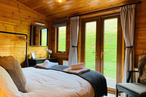 a bedroom with a bed in a room with windows at Luxury Farm Cabin in the Heart of Wales in Cowbridge