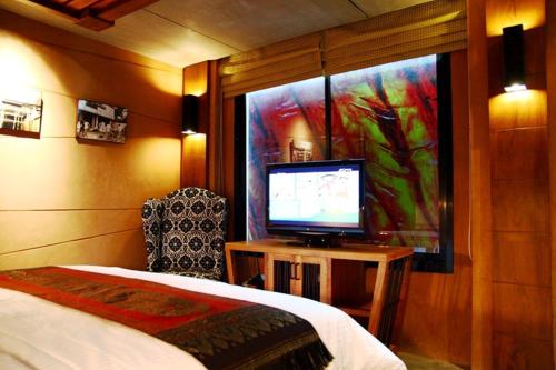 a bedroom with a bed and a tv and a window at The Fusion Suites in Bangkok