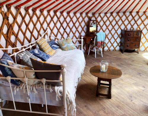 Zimmer mit einem Bett und einem Tisch in einer Jurte in der Unterkunft Beautiful Rural Yurt with Wood Fired hot tub 