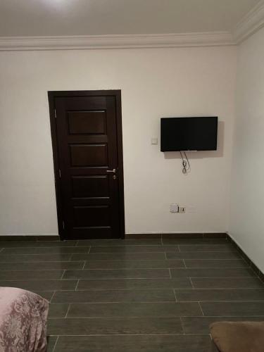 um quarto com uma televisão de ecrã plano numa parede branca em Cosy 3 bedroom holiday apartment for rent em Sakumona