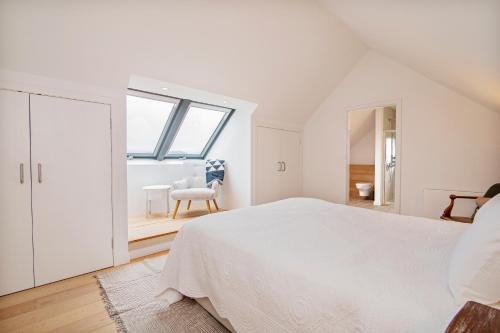Un dormitorio blanco con una cama grande y una ventana en Luxury coastal retreat with stunning views, en Aultbea